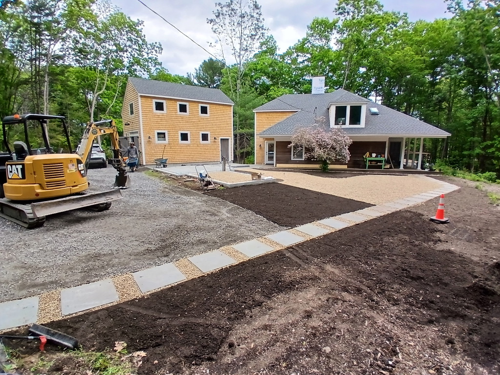 A new bluestone walkway taking shape beside a freshly graded yard in a residential landscape project